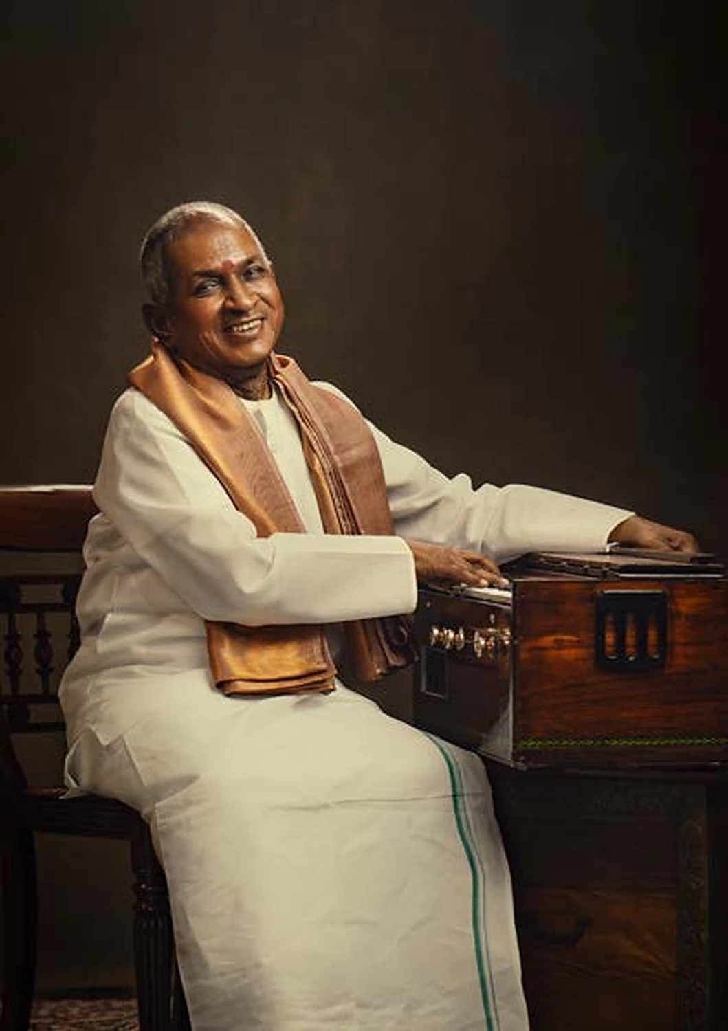 Portrait of musician Ilaiyaraaja seated beside an instrument