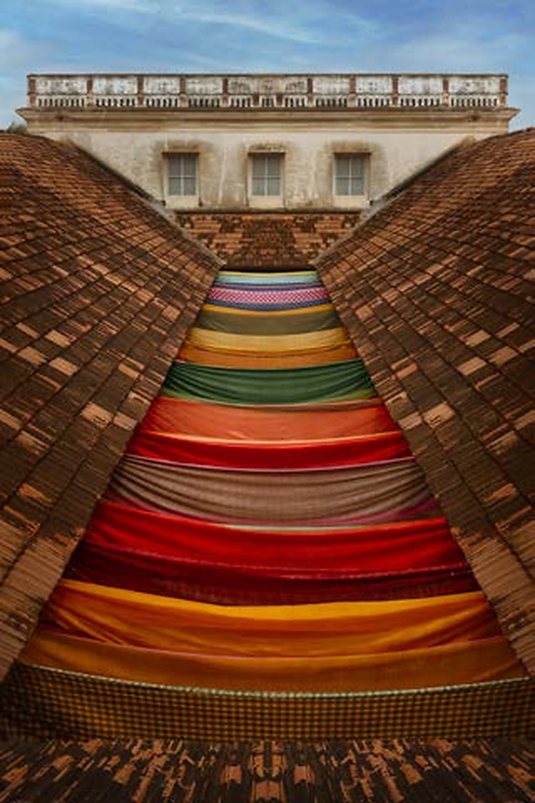 Chettinad roofs framing a vivid stack of traditional textiles