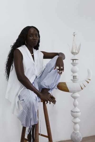 Portrait of Luma Nascimento beside one of her sculptures