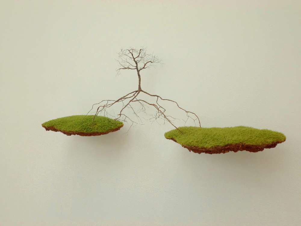Entre Dos Aguas by Jorge Mayet, a tree suspended between two floating pieces of earth