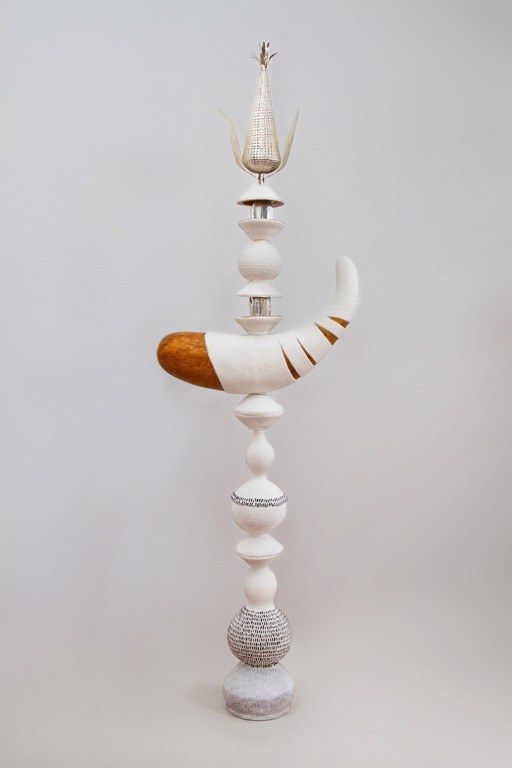 A tall stacked sculpture in white ceramic with gilding and beadwork