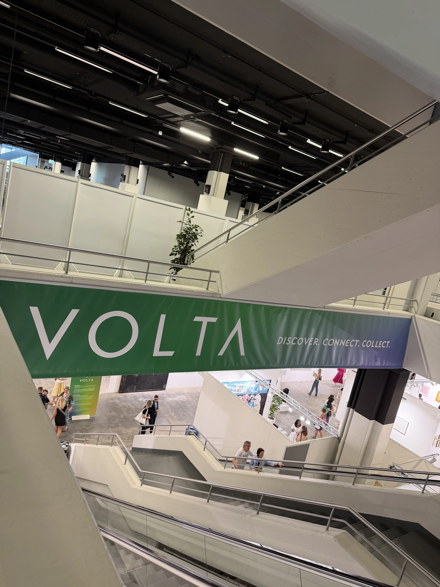 The VOLTA banner hanging above the stairwells of the fair building in Basel, reading Discover, Connect, Collect