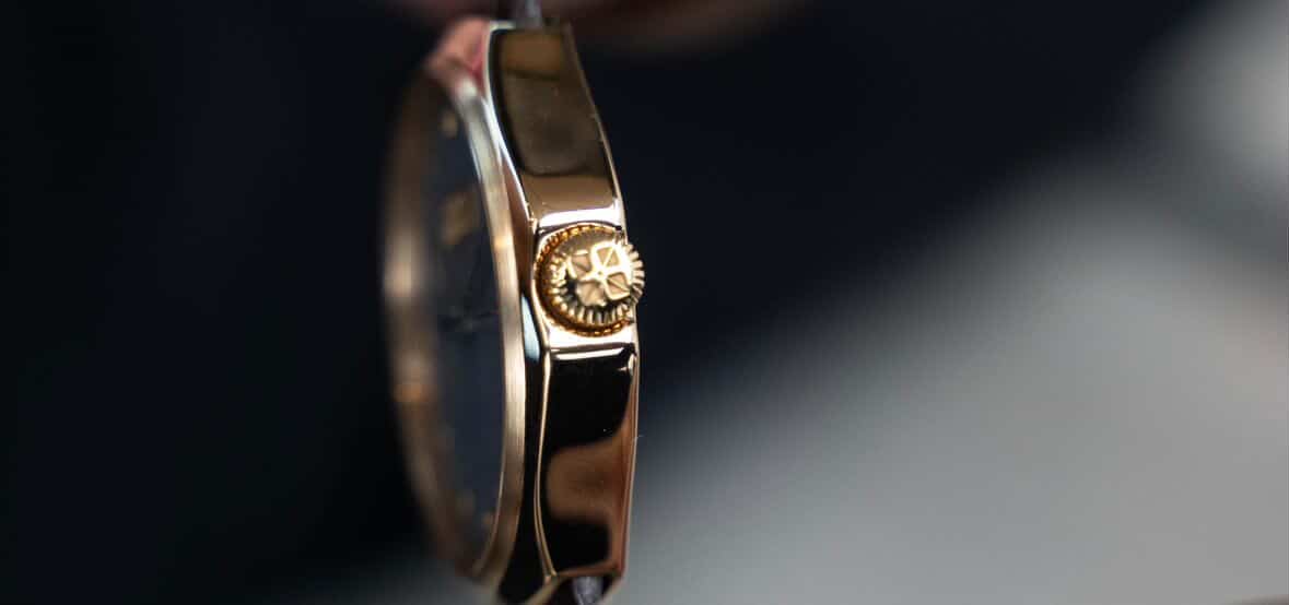Extreme close view of the polished rose gold case flank and the engraved crown of the Zimbali 000
