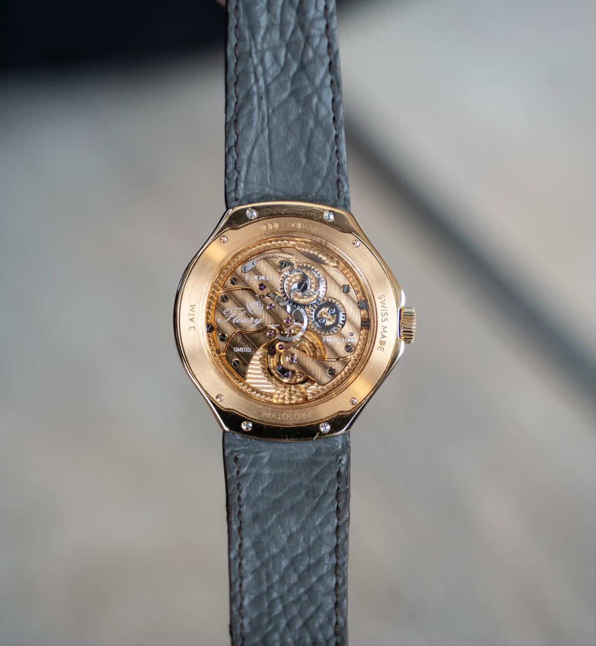 The Zimbali 000 caseback on a grey grained leather strap, the Fleury signed movement visible through sapphire and the case engraved prototype