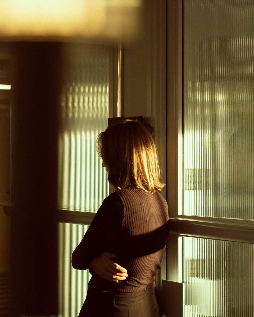 A guest standing in golden evening light by the ribbed glass windows